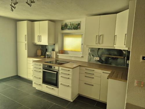 eine Küche mit weißen Schränken und einem Herd mit Backofen in der Unterkunft Apartment EG in Lendorf