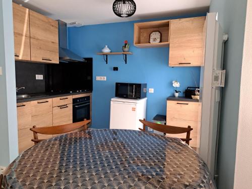 une cuisine avec des murs bleus et une table et des chaises dans l'établissement Bleu Bonheur, à Jonzac
