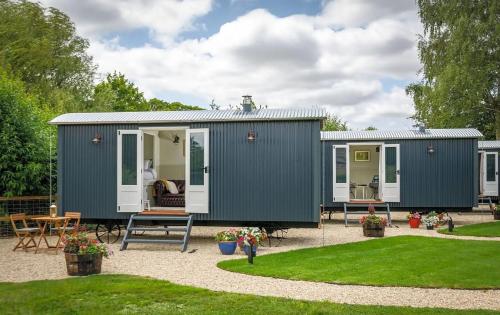 a green and white tiny house in a garden at The Red Lion - Shepherd Huts in Witney