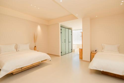 two beds in a bedroom with white walls and white floors at Yunyuan Private Hot Spring Bed and Breakfast in Sanying