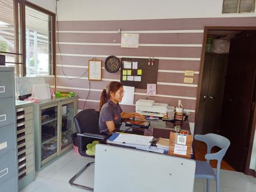 a woman sitting at a desk in a room at Goldenville in Ban Du