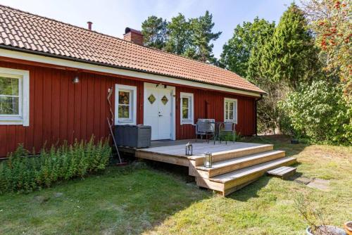 a red house with a wooden deck in front of it at Hus Skärgården in Figeholm