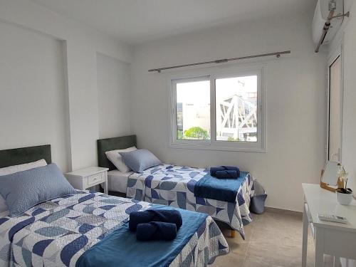 a bedroom with two beds and a window at Hawaii Holiday Apartment 41 in Limassol