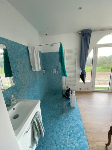 La salle de bains est pourvue d'une baignoire et d'un lavabo avec du carrelage bleu. dans l'établissement Logement entier dans manoir à Trouville vue mer, à Trouville-sur-Mer