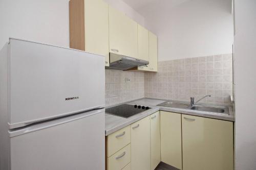 a white kitchen with a sink and a refrigerator at Apartments Brnic in Baška