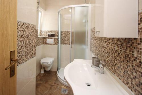 a bathroom with a toilet and a sink and a shower at Apartments Brnic in Baška