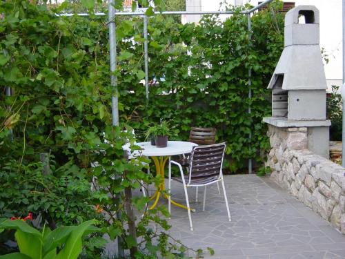 a patio with a table and chairs in a garden at Apartments Brnic in Baška