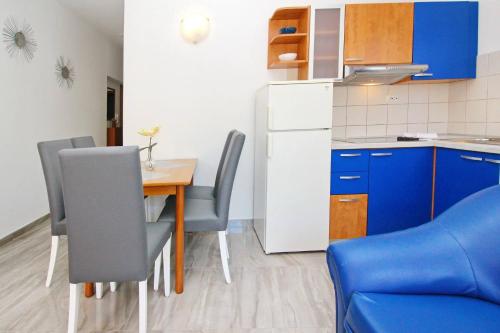 a small kitchen with a table and blue cabinets at Apartments Brnic in Baška