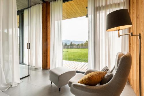 a living room with a chair and a lamp and a window at Proste Chwile in Tylicz