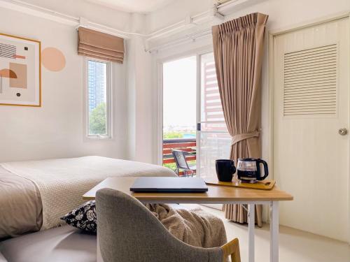 a bedroom with a bed and a desk with a laptop at The Giftown Bangkok, Talat Phlu in Thonhuri