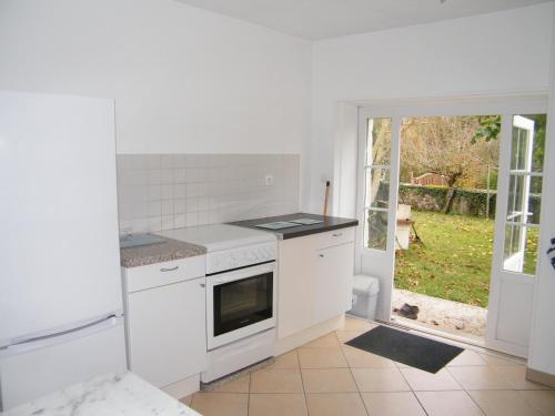 eine weiße Küche mit einem Herd Top-Backofen neben einer Tür in der Unterkunft La Caz en Sol Charentais - Le Fâ in Montpellier-de-Médillan