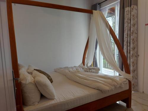 a bed with white sheets and pillows next to a window at Tea Hills Lake in Hatton