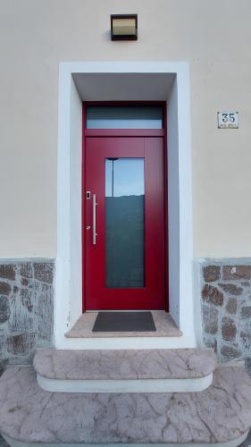 a red door in a white building with a stone wall at Over the Castle Apartment in Trento