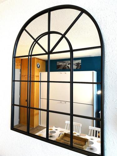 un miroir en forme d'arche suspendu à un mur dans l'établissement Studio Plagne Centre Aconcagua, à La Plagne Tarentaise