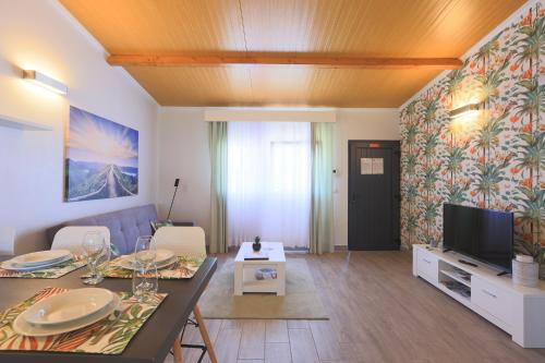 a living room with a dining table and a television at Parrots`Village in Rabo de Peixe