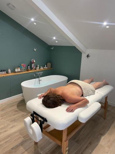 a man laying in a bath tub in a bathroom at Hitton Séjours Nature in Biran