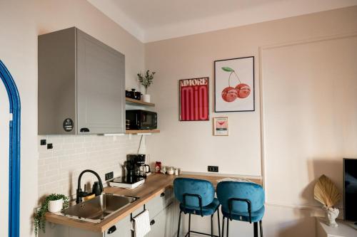 a kitchen with a sink and two blue bar stools at Decebal Modern Studio - Central Arad in Arad