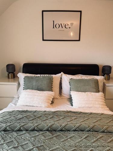 a bed with white pillows and a sign that says love at Beach Vista Apartment Three in Barmouth in Barmouth