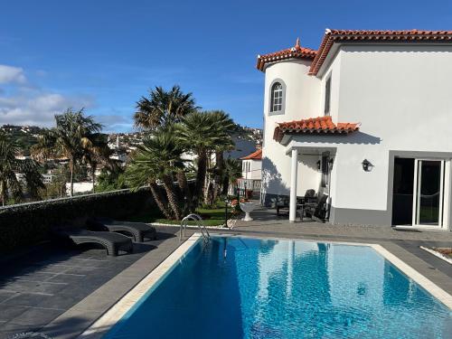 a villa with a swimming pool in front of a house at Funchal Apt- Sleeps 2 - Pool & Garden - Madeira in Funchal