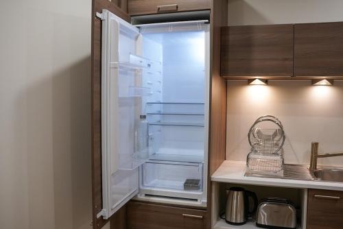 un réfrigérateur vide avec sa porte ouverte dans une cuisine dans l'établissement T2 cosy au cœur de Perpignan, à Perpignan