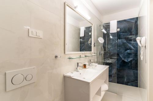 a white bathroom with a sink and a mirror at Heritage hotel Santa Lucia in Split