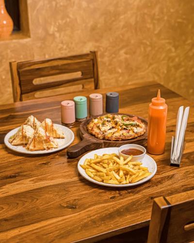two pizzas and french fries on a wooden table at Yashvrinda in Mandor
