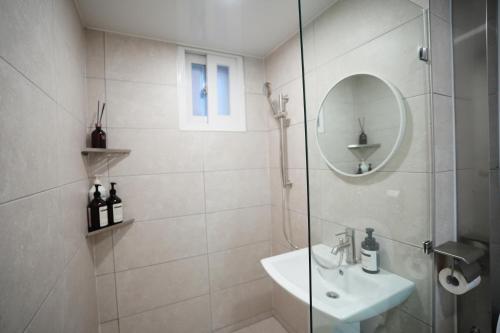 a white bathroom with a sink and a mirror at Residence Unicorn in Seoul