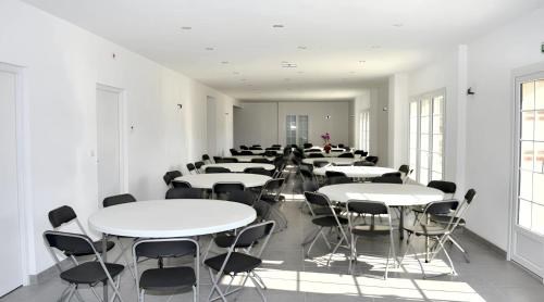 Cette grande chambre comprend des tables et des chaises blanches. dans l'établissement Grande maison accueillante à Saint-Épain avec salle de réception, à Saint-Épain