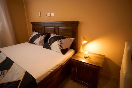 a bedroom with a bed and a lamp on a table at AMP Lodge in Kumasi