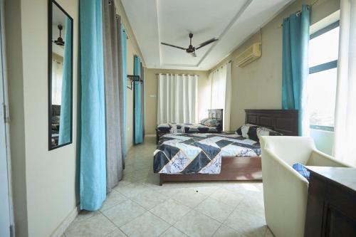 a bedroom with two beds with blue curtains at AMP Lodge in Kumasi
