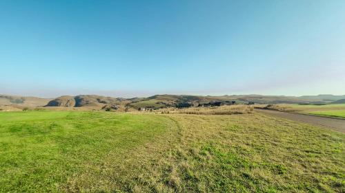 a field of grass with a road in the distance at Highland Peace Haven In Dullstroom in Dullstroom