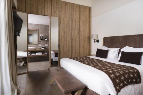 Pokój hotelowy z dużym łóżkiem i lustrem w obiekcie Grand Hotel Courmayeur Mont Blanc, by R Collection Hotels w mieście Courmayeur