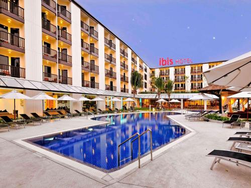 a hotel with a swimming pool in front of a building at Ibis Phuket Kata in Kata Beach