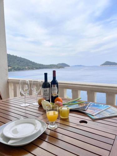 a table with wine bottles and glasses on a balcony at Terrace apartment with panoramic seaview in Ubli