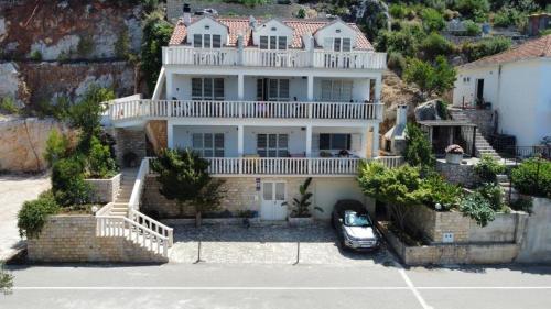 a large white house with a car parked in front of it at Terrace apartment with panoramic seaview in Ubli