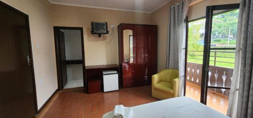 a bedroom with a bed and a tv and a balcony at Hotel Floresta in Poços de Caldas