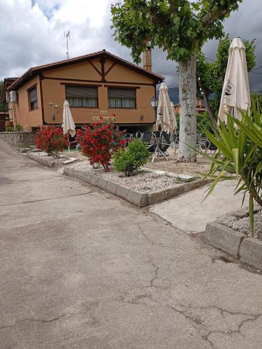 a house with umbrellas and flowers and a building at La Muralla de Gredos Hotel Rural in Madrigal de la Vera