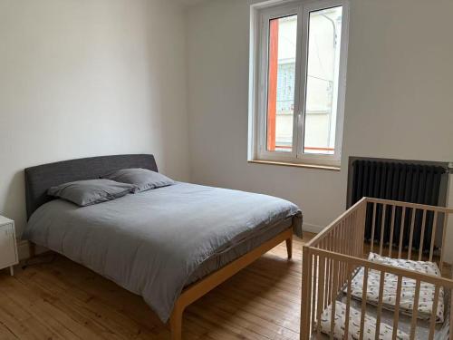 a bed in a white room with a window at Appart cœur de ville belle vue in Vichy