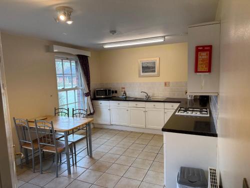 a kitchen with white cabinets and a table with chairs at Netley Hall in Shrewsbury