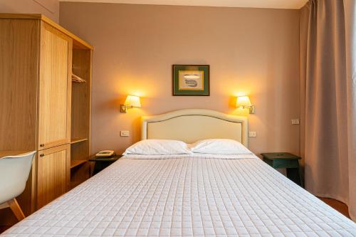 a bedroom with a large white bed with two lamps at Hotel Pescille Country House - Tuscany Charme in San Gimignano