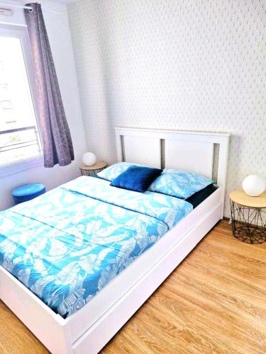 une chambre avec un lit avec des draps bleus et une fenêtre dans l'établissement 7 people, 5 MINUTES Paris, Metro, Parking, à Saint-Denis