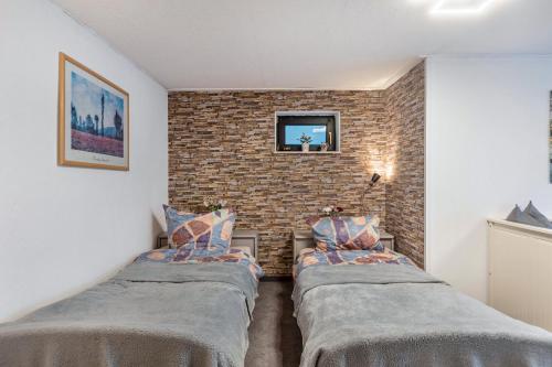two beds in a room with a brick wall at Fewo Am Wiesbachtal in Wehrheim