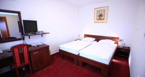 a bedroom with a bed and a desk and a mirror at Hotel Orion in Ivanec