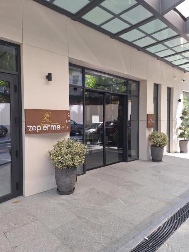 an office building with glass doors and potted plants at Zepterme Apartman 012 in Vrnjačka Banja