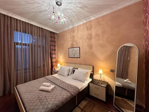 a bedroom with a bed with a mirror and a chandelier at Serenity apart by Bakuapart in Baku