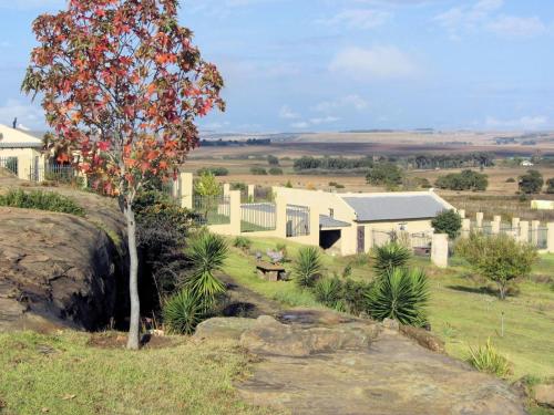 a tree in a field next to a building at Vreugde Gasteplaas in Warden
