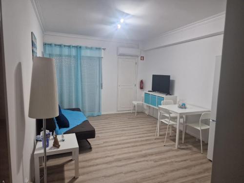 a room with a bed and a table and a tv at Apartamento em Quarteira in Quarteira