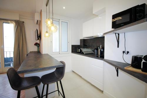 une cuisine avec un comptoir, une table et des chaises dans l'établissement CLEMENCEAU 2 Studio Confortable Clim et Dressing Proche Gare, à Nice