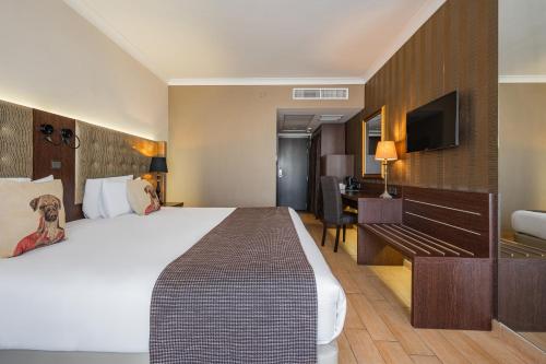 a hotel room with a large bed and a desk at AX The Victoria Hotel in Sliema