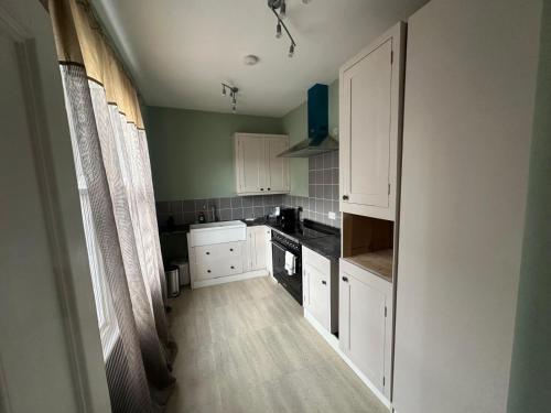 a kitchen with white cabinets and black appliances at Cozy flat by Birmingham Canals & City Centre in Birmingham